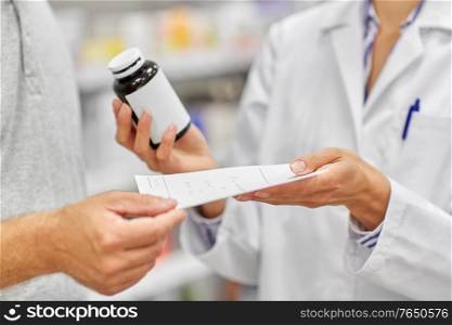 medicine, pharmaceutics, healthcare and people concept - pharmacist with drug taking prescription from male customer at drugstore. pharmacist and customer with medicine at pharmacy