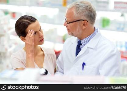 medicine, pharmaceutics, healthcare and people concept - senior apothecary offering drug for female customer suffering from headache at pharmacy. apothecary offering cure to customer at pharmacy