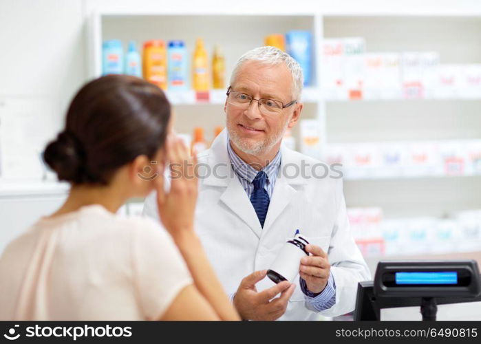 medicine, pharmaceutics, healthcare and people concept - senior apothecary with drug and female customer suffering from headache at pharmacy. apothecary with cure and customer at pharmacy. apothecary with cure and customer at pharmacy