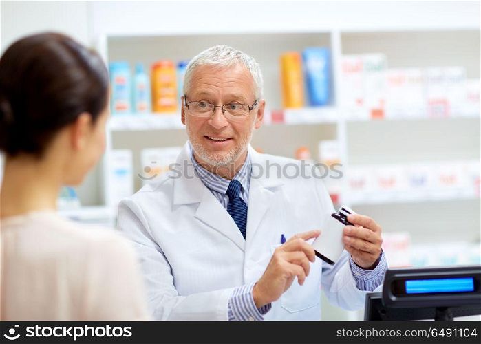 medicine, pharmaceutics, healthcare and people concept - senior apothecary with drug and female customer at pharmacy. apothecary with cure and customer at pharmacy. apothecary with cure and customer at pharmacy