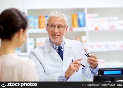 medicine, pharmaceutics, healthcare and people concept - senior apothecary with drug and female customer at pharmacy. apothecary with cure and customer at pharmacy. apothecary with cure and customer at pharmacy