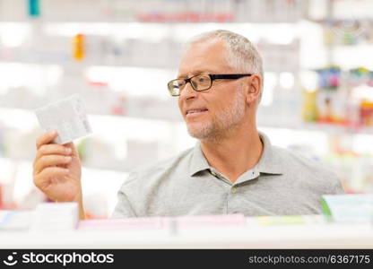 medicine, pharmaceutics, healthcare and people concept - senior male customer with drug at pharmacy. senior male customer with drug at pharmacy