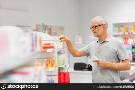 medicine, pharmaceutics, healthcare and people concept - senior male customer with drug at pharmacy. senior male customer with drug at pharmacy