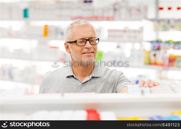 medicine, pharmaceutics, healthcare and people concept - senior male customer with drug at pharmacy. senior male customer with drug at pharmacy. senior male customer with drug at pharmacy