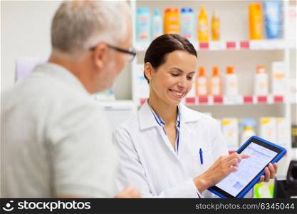 medicine, pharmaceutics, healthcare and technology concept - happy apothecary and senior customer with tablet pc computer at pharmacy. apothecary and customer with tablet pc at pharmacy