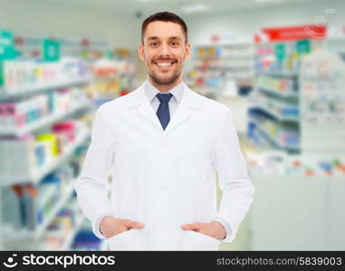 medicine, pharmacy, people, health care and pharmacology concept - smiling male pharmacist in white coat over drugstore background