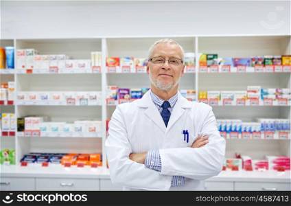 medicine, pharmacy, people, health care and pharmacology concept - smiling senior male pharmacist in white coat at drugstore