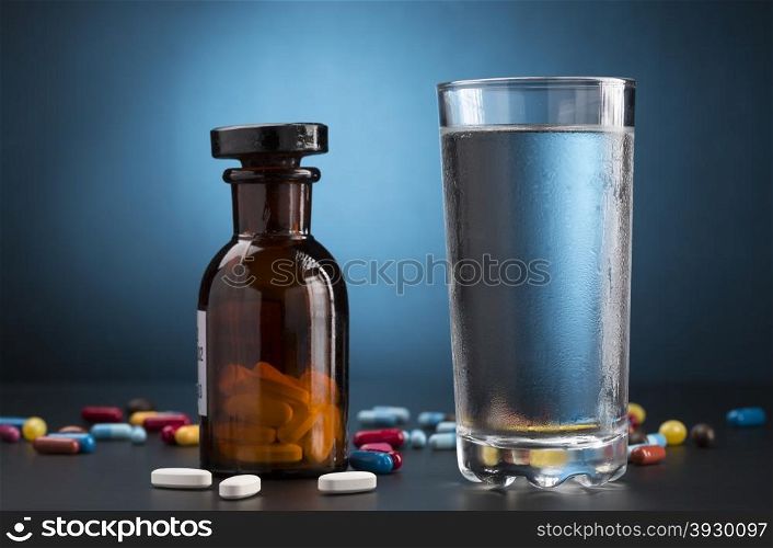 Medicine pills bottle and glass of drink water. Medicine pills bottle and glass of cold drink water