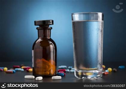 Medicine pills bottle and glass of drink water. Medicine pills bottle and glass of cold drink water