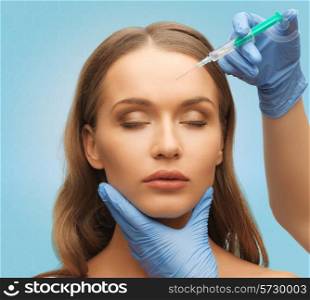 medicine, plastic surgery, beauty, health and people concept - hands in medical glove with syringe making injection to beautiful woman face over blue background