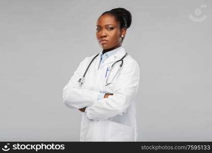 medicine, profession and healthcare concept - african american female doctor in white coat with crossed hands and stethoscope over background. african american female doctor with stethoscope