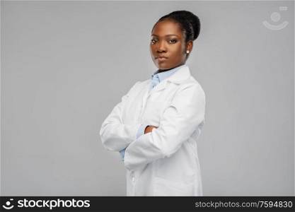 medicine, profession and healthcare concept - african american female doctor or scientist in white coat with crossed hands over grey background. african american female doctor or scientist