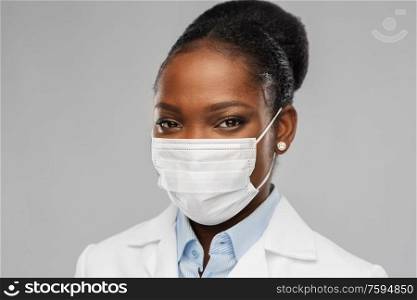 medicine, profession and healthcare concept - african american female doctor or scientist in protective facial mask over grey background. african american female doctor in facial mask