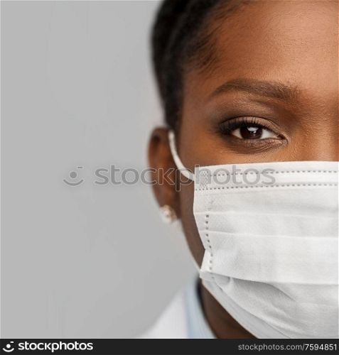 medicine, profession and healthcare concept - close up of african american female doctor or scientist in protective facial mask over grey background. african american female doctor in facial mask