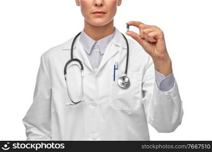 medicine, profession and healthcare concept - close up of female doctor with stethoscope holding pill over white background. close up of female doctor holding medicine pill
