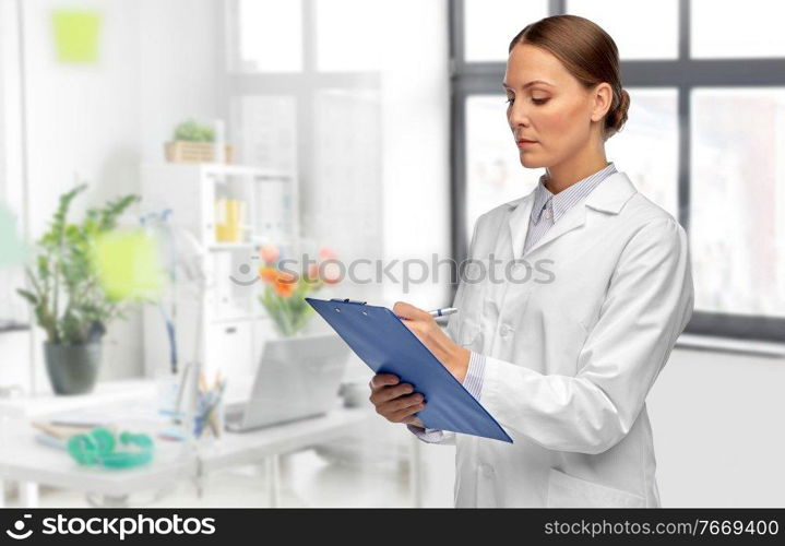 medicine, profession and healthcare concept - female doctor in white coat with clipboard and pen writing medical report over medical office at hospital on background. female doctor with clipboard at hospital