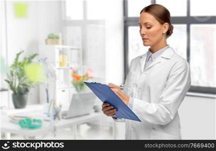 medicine, profession and healthcare concept - female doctor in white coat with clipboard and pen writing medical report over medical office at hospital on background. female doctor with clipboard at hospital