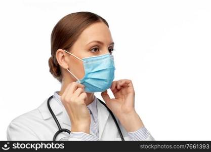 medicine, profession and healthcare concept - female doctor in white coat with stethoscope wearing medical mask. happy female doctor wearing medical mask