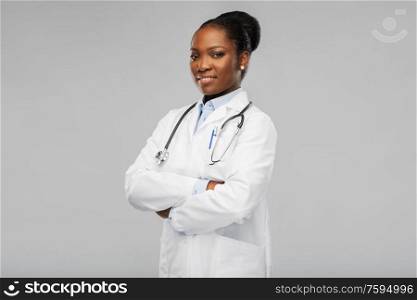 medicine, profession and healthcare concept - happy smiling african american female doctor in white coat with stethoscope over background. african american female doctor with stethoscope