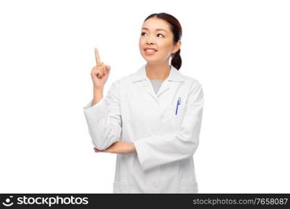 medicine, profession and healthcare concept - happy smiling asian female doctor in white coat pointing finger up. happy asian female doctor pointing finger up