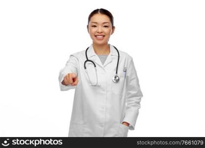 medicine, profession and healthcare concept - happy smiling asian female doctor in white coat pointing to camera. happy asian female doctor pointing to camera