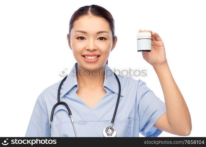 medicine, profession and healthcare concept - happy smiling asian female doctor or nurse in blue uniform with stethoscope holding jar of pills over white background. smiling asian female doctor or nurse with medicine