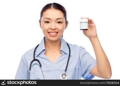 medicine, profession and healthcare concept - happy smiling asian female doctor or nurse in blue uniform with stethoscope holding jar of pills over white background. smiling asian female doctor or nurse with medicine