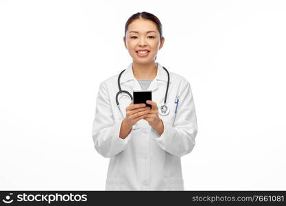 medicine, profession and healthcare concept - happy smiling asian female doctor or nurse in blue uniform with stethoscope using smartphone over white background. happy asian female doctor or nurse with smartphone