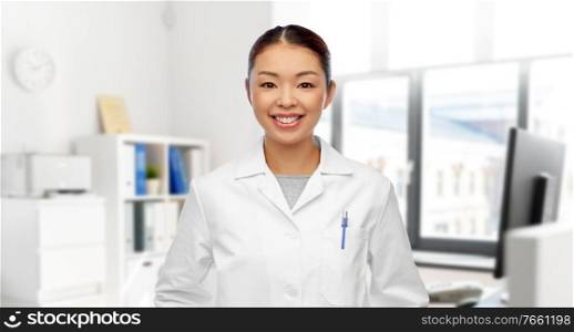 medicine, profession and healthcare concept - happy smiling asian female doctor or scientist in white coat over medical office at hospital on background. happy smiling asian female doctor at hospital