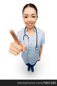 medicine, profession and healthcare concept - happy smiling asian female doctor or nurse with stethoscope in blue uniform pointing to camera. happy asian female doctor pointing to camera
