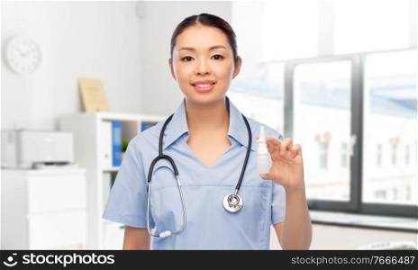 medicine, profession and healthcare concept - happy smiling asian female doctor or nurse in blue uniform with stethoscope and nasal spray over hospital background. smiling asian female doctor or nurse with medicine