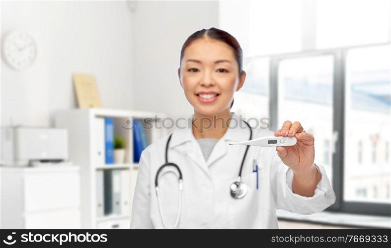 medicine, profession and healthcare concept - happy smiling asian female doctor with stethoscope and thermometer over medical office at hospital on background. smiling asian female doctor with thermometer