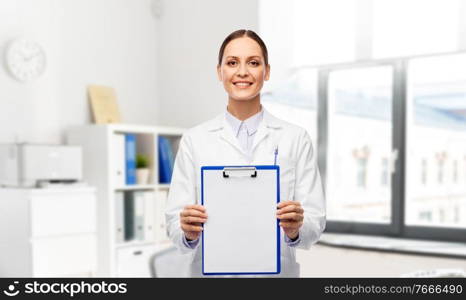 medicine, profession and healthcare concept - happy smiling female doctor in white coat showing clipboard over hospital background. smiling female doctor with clipboard at hospital
