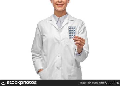 medicine, profession and healthcare concept - happy smiling female doctor in white coat holding pills over white background. smiling female doctor holding medicine pills