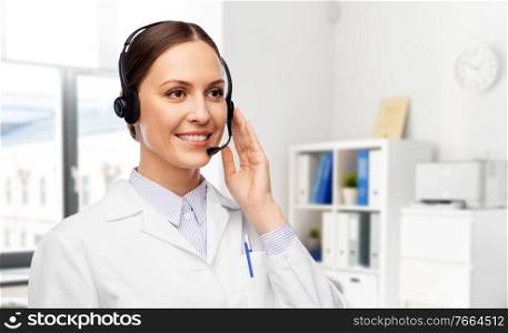 medicine, profession and healthcare concept - happy smiling female doctor with headset over hospital background. smiling female doctor with headset