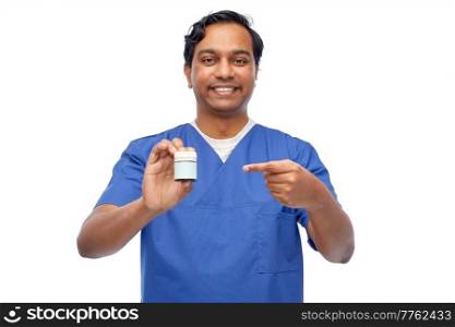 medicine, profession and healthcare concept - happy smiling indian doctor or male nurse holding jar of pills over white background. indian doctor or male nurse holding medicine