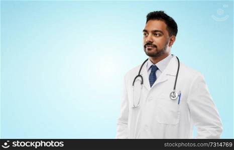 medicine, profession and healthcare concept - indian male doctor in white coat with stethoscope over blue background. indian male doctor with stethoscope