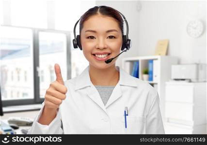medicine, profession and healthcare concept - portrait of happy smiling asian female doctor in headset over medical office at hospital on background. smiling asian female doctor in headset at hospital