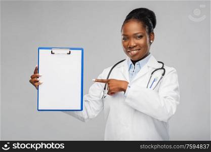 medicine, profession and healthcare concept - smiling african american female doctor in white coat with clipboard and stethoscope over grey background. african american female doctor with clipboard