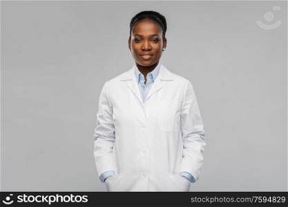 medicine, profession and healthcare concept - smiling african american female doctor or scientist in white coat over grey background. happy african american female doctor or scientist