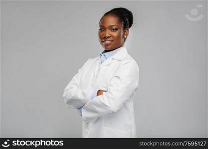 medicine, profession and healthcare concept - smiling african american female doctor or scientist in white coat with crossed hands over grey background. happy african american female doctor or scientist