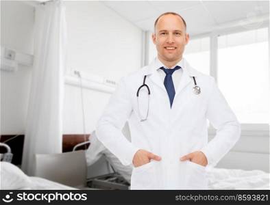 medicine, profession and healthcare concept - smiling male doctor with stethoscope over hospital ward background. smiling male doctor with stethoscope at hospital