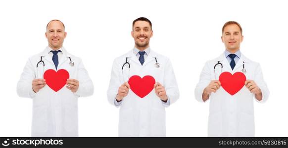 medicine, profession, cardiology, charity and health care concept - three smiling male doctors with red heart and stethoscope