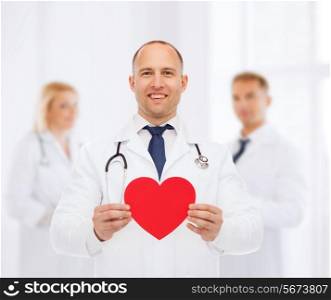 medicine, profession, charity and healthcare concept - smiling male doctor with red heart and stethoscope over group of medics