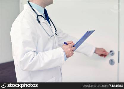 medicine, profession, healthcare and people concept - close up of doctor with clipboard and stethoscope at hospital opening door. close up of doctor with clipboard at hospital door