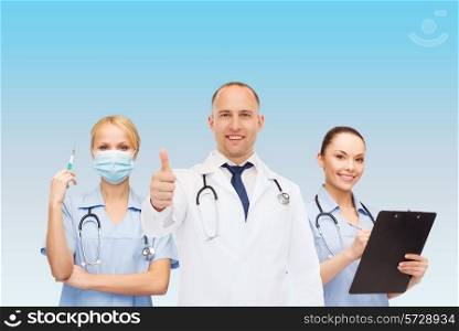 medicine, profession, teamwork and healthcare concept - international group of smiling medics or doctors with clipboard and stethoscopes with showing thumbs up over blue background