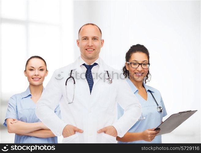 medicine, profession, teamwork and healthcare concept - international group of smiling medics or doctors with clipboard and stethoscopes over hospital background