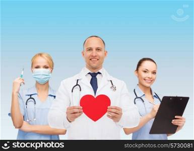 medicine, profession, teamwork and healthcare concept - international group of smiling medics or doctors holding red paper heart shape clipboard and stethoscopes over blue background
