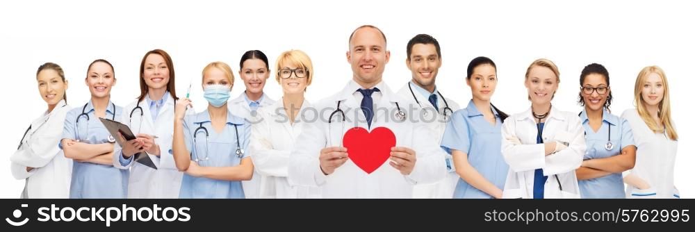 medicine, profession, teamwork and healthcare concept - international group of smiling medics or doctors with clipboard and stethoscopes holding red paper heart shape over white background