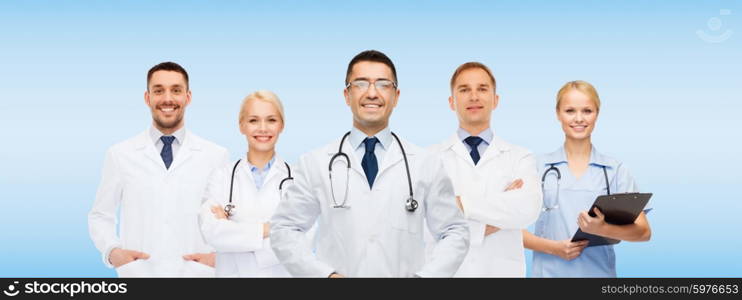 medicine, profession, teamwork and healthcare concept - international group of smiling medics or doctors with clipboard and stethoscopes over blue background